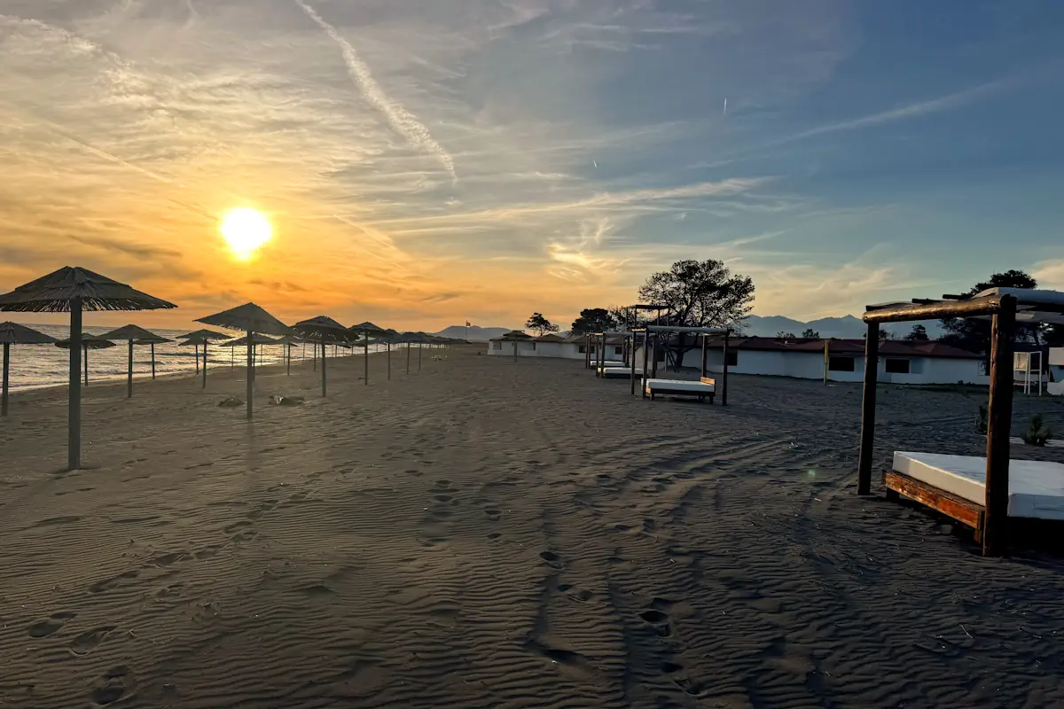 View of the long sandy stretch of Ada Bojana island with daybeds and parasols at sunset
