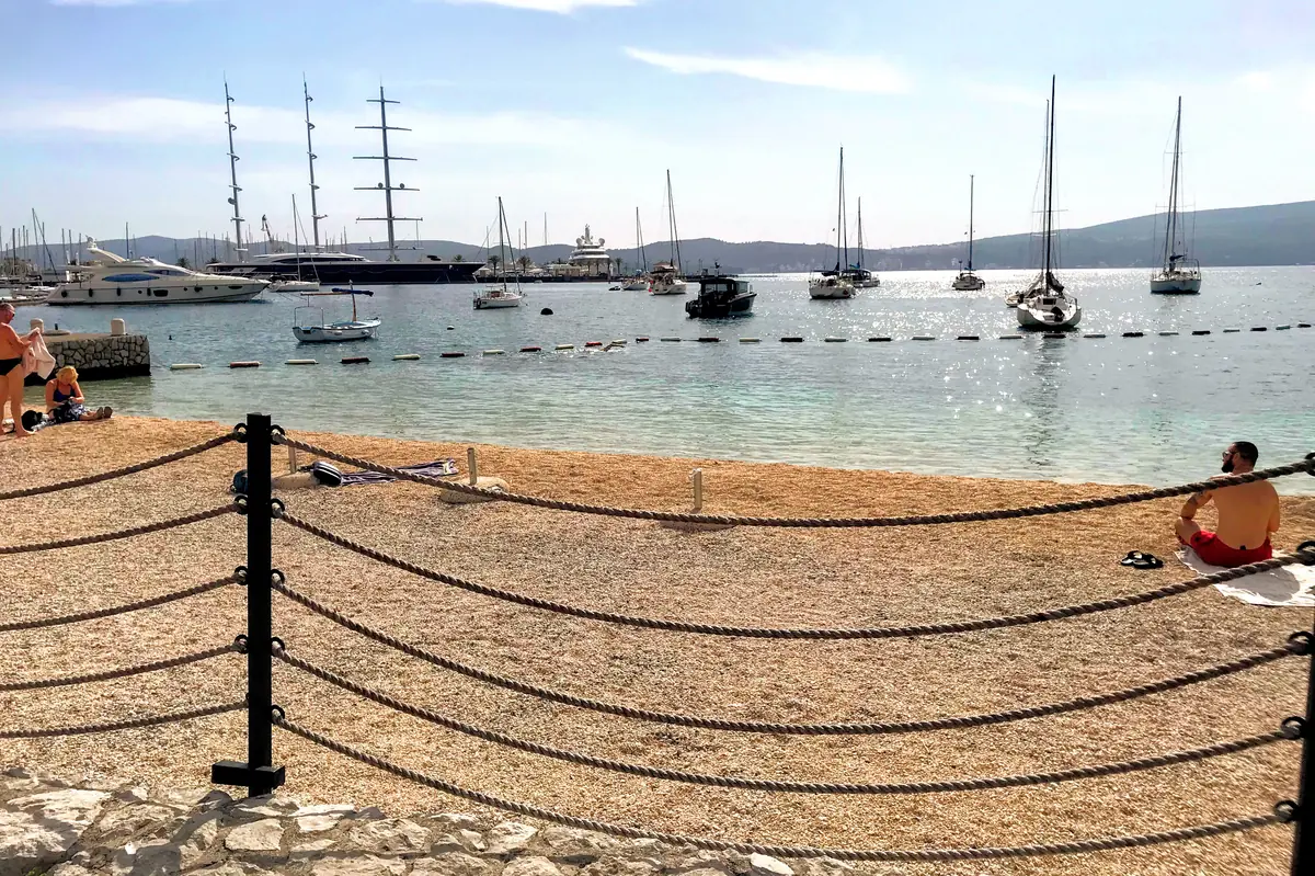 Amaia Beach Tivat featuring super yachts, fishing boats and pebbly shore