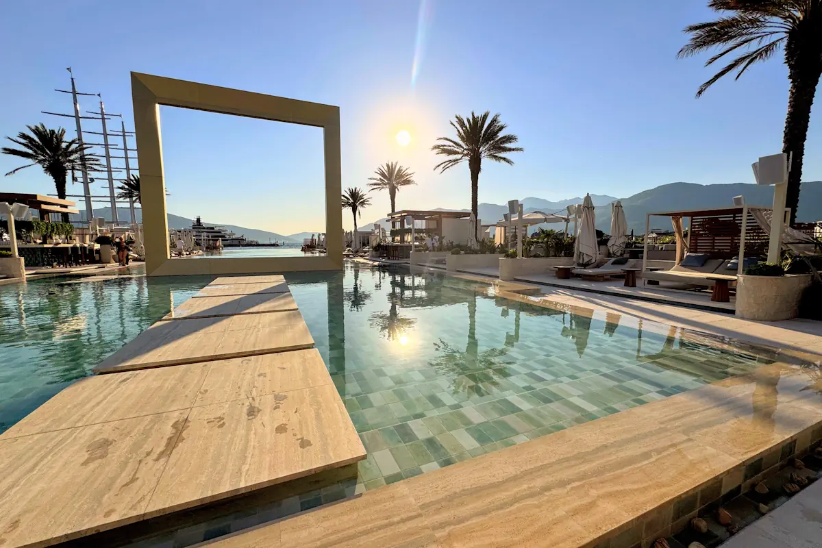 Aura Beach Porto Montenegro featuring the 64-meter infinity pool, line of palms, and super-yacht backdrop