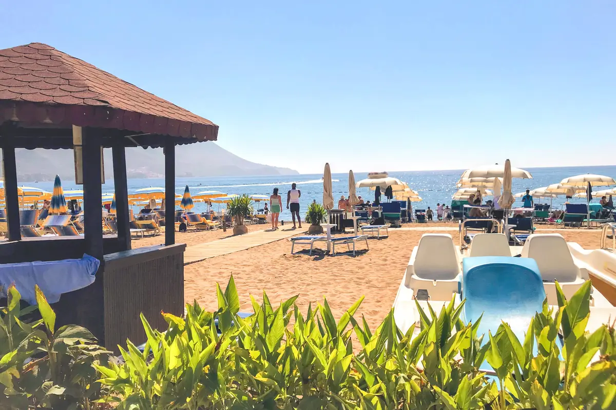 The golden pebbles, sun loungers, and parasols, near Zavala Peninsula, Becici Beach