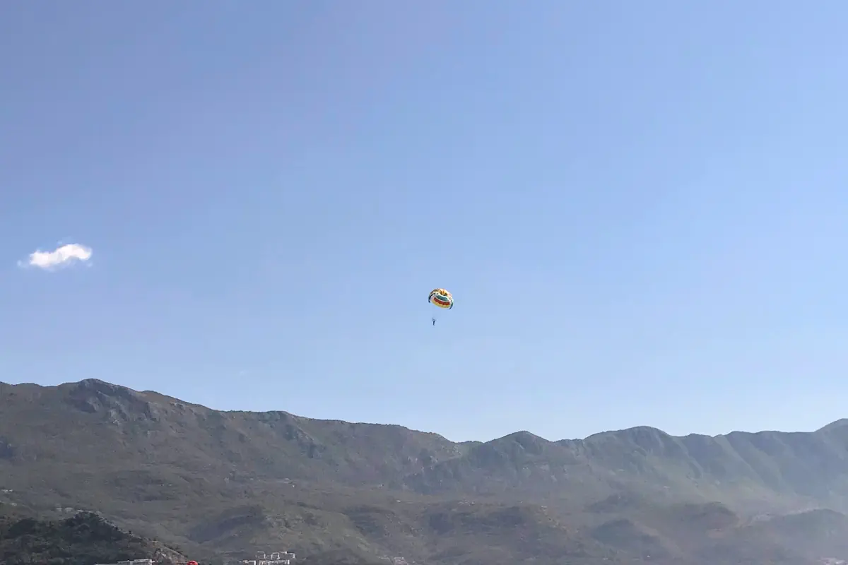 Tandem paraglider descending smoothly over the turquoise waters of Becici Bay