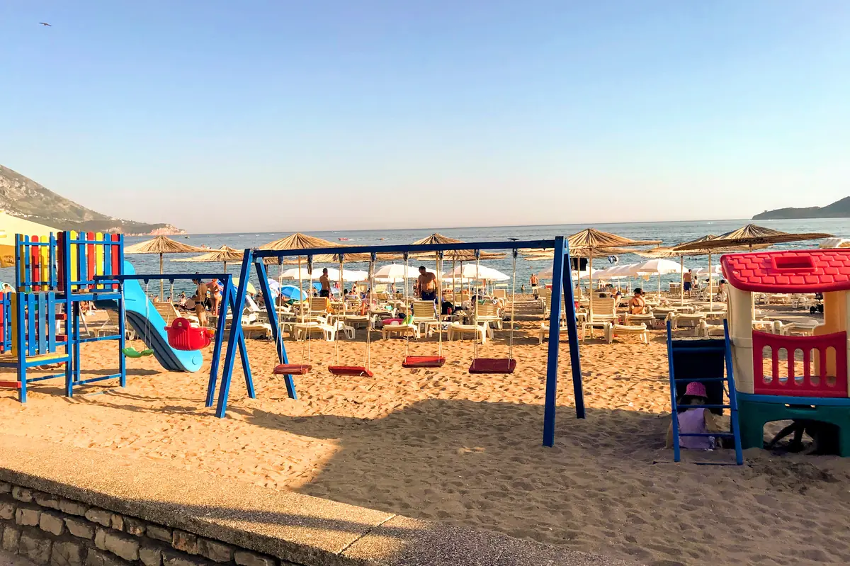 Becici Beach central part with children's playground, loungers, and parasols