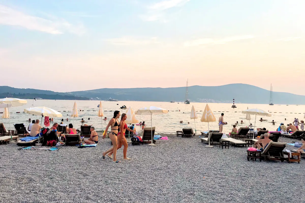 Belane Beach Tivat with sun loungers and saiboats in the background near the town center