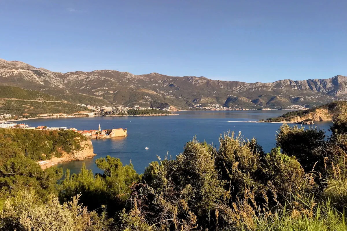 Aerial view of Budva Old Town walls incl. the Citadel jutting into the blue Adriatic overlooking Sveti Nikola Island