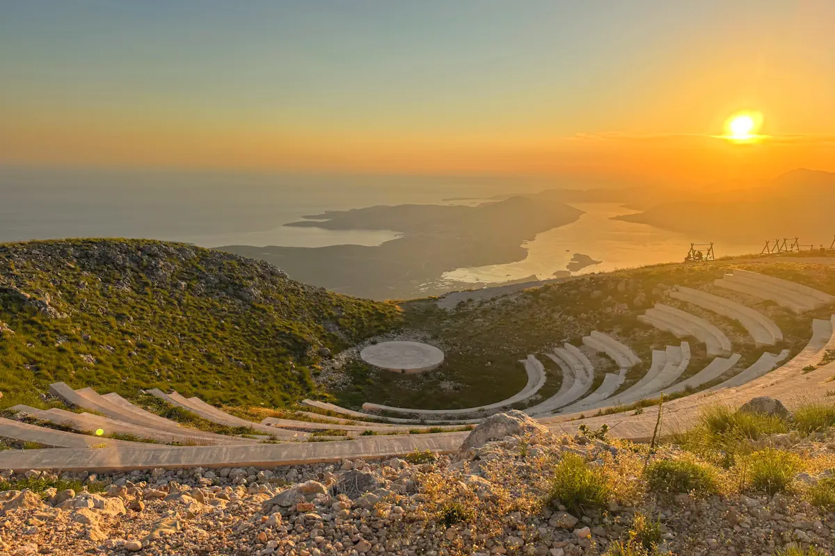 The layered stone curved rows of the open-air lookout amphitheater catching the warm golden hour light above the bay contours