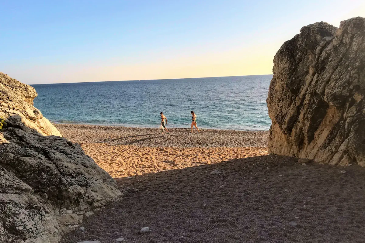 Two people walking between the boulders on Perazica Do Beach near Petrovac