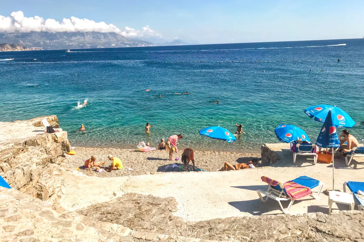 The tiny pebble stretch of Ploce Beach on the northern end with parasols and kids playing