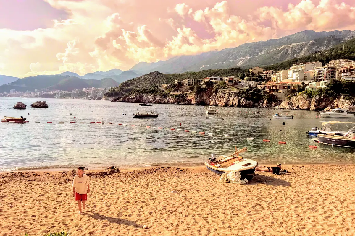 Przno Beach near Sveti Stefan overlooking the Budva Riviera with fishing boats and child