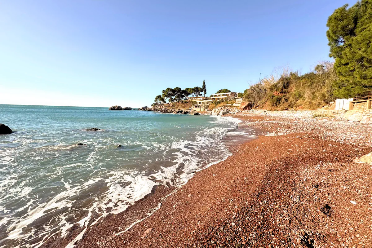 Red Beach near Bar with distinct crimson pebbles and surrounding green pine trees