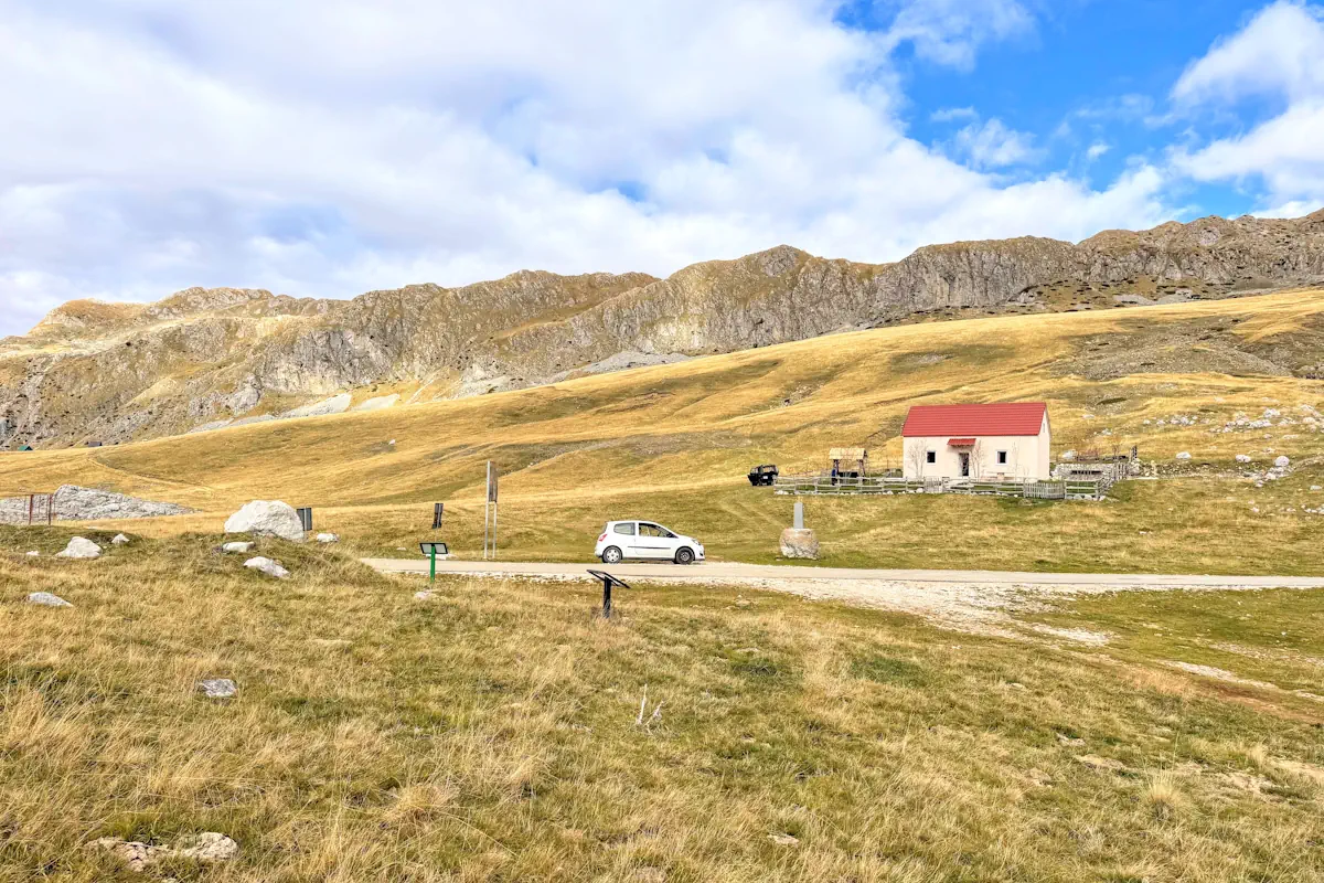 White compact rental car driving through the mountain passes of Montenegro