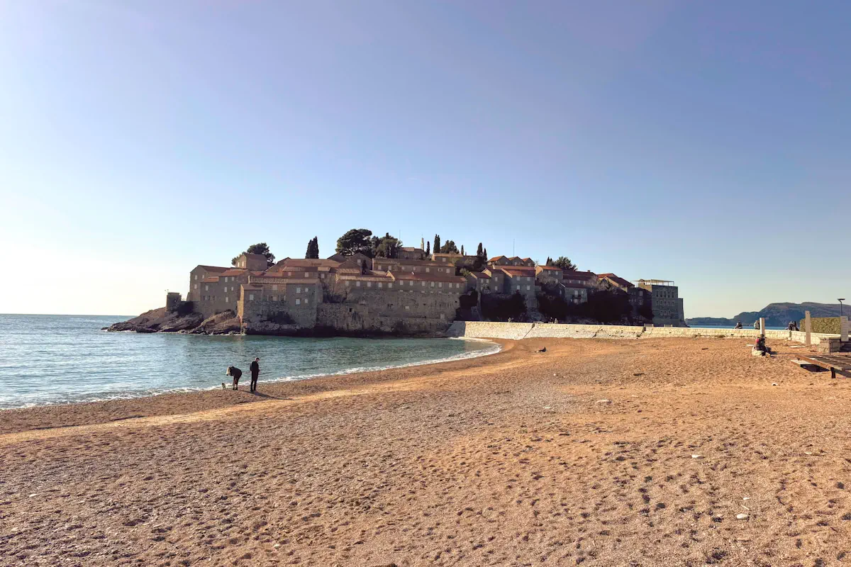 View of Sveti Stefan island with its red roofs and stone walls against the turquoise sea