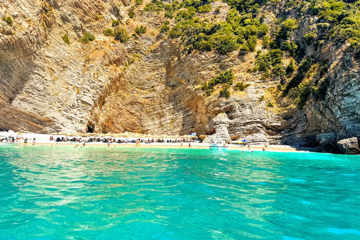 Vezir's Beach with white pebbles and plunging cliffs with taxi boat and sunseekers