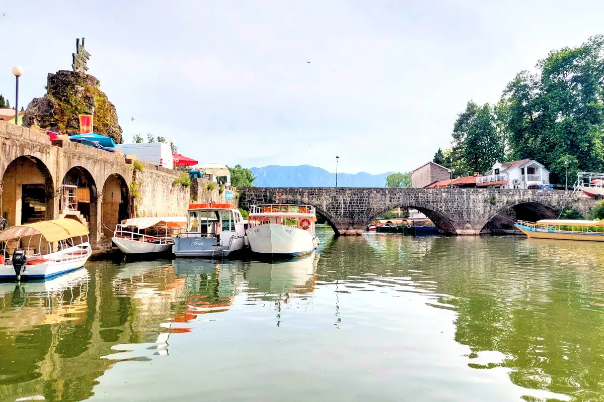 Virpazar Stone Bridge with the monument in the beackground and boats