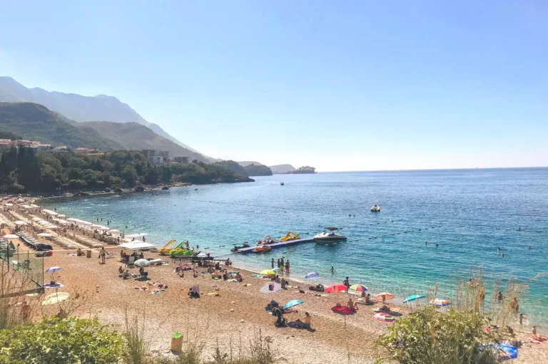 Aerial View of Kamenovo Beach between Budva and Sveti Stefan with sun loungers and pier, turquoise waters