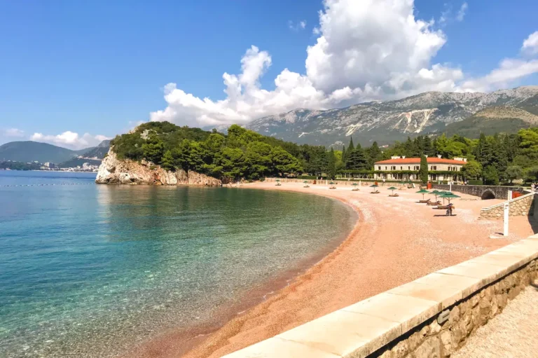 Aerial View of Milocer Beach (King's Beach) from the hiking trail to Sveti Stefan and its smooth pink pebbles, with summer residence of Karađorđević royal dynasty in the background