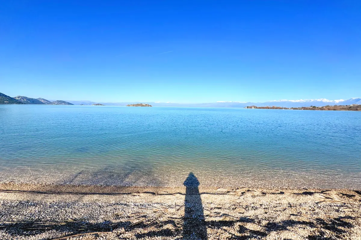 Pebbly Murici Beach on the shores of Lake Skadar overlooking the mountains of Albania