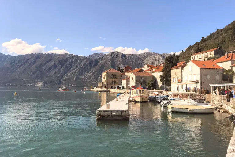 Waterfront dining terraces in Perast with a view of Our Lady of the Rocks and the Bay of Kotor, Montenegro.