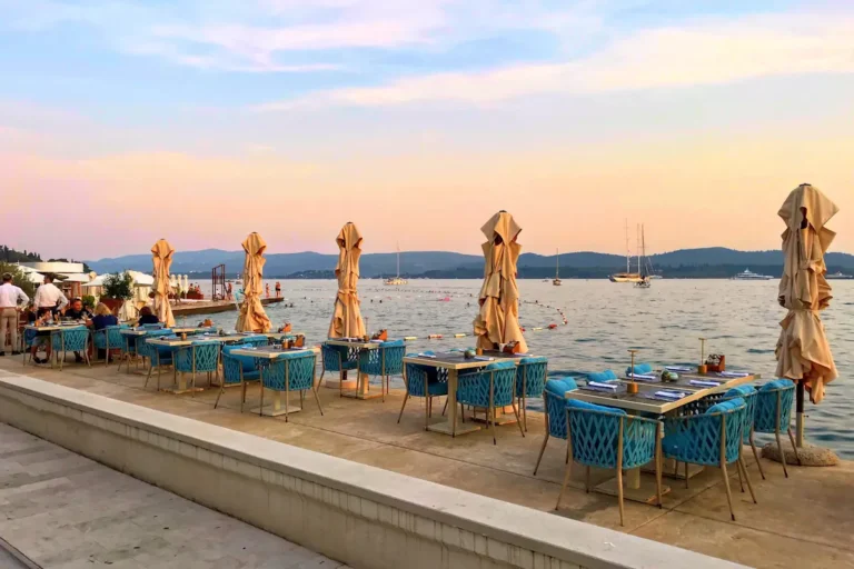 Outdoor terrace of a top-rated restaurant in Tivat, Montenegro, showing an elegant dinner setup with warm ambient lighting.