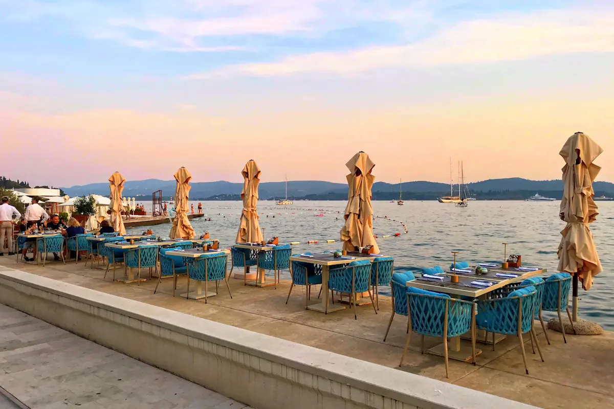 Outdoor terrace of a top-rated restaurant in Tivat, Montenegro, showing an elegant dinner setup with warm ambient lighting.