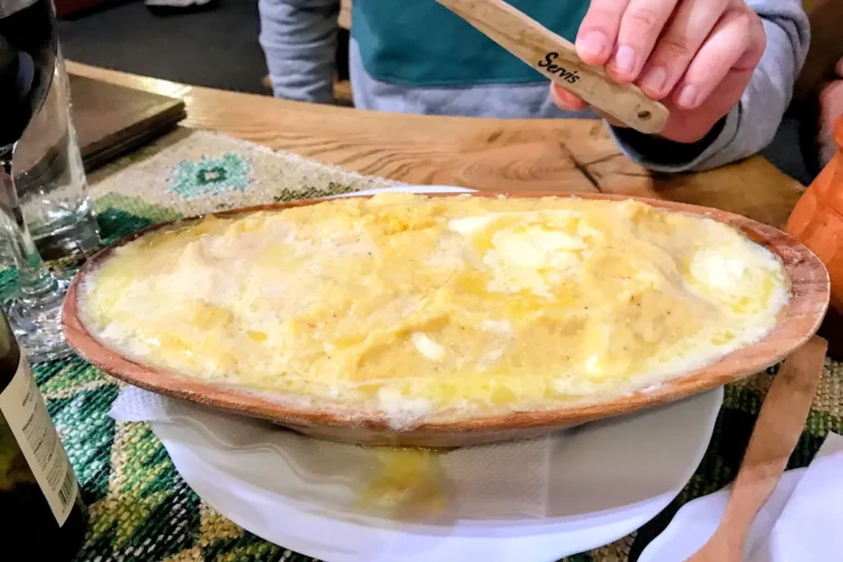 A bowl of traditional Montenegrin cicvara, a rich and creamy melted cheese and flour dish served hot.