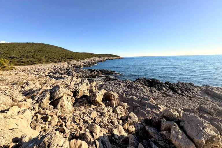 The rocky, uninhabited southern coastline of the Luštica Peninsula in Montenegro, featuring the sharp limestone cliffs used for coasteering and adventure tours.