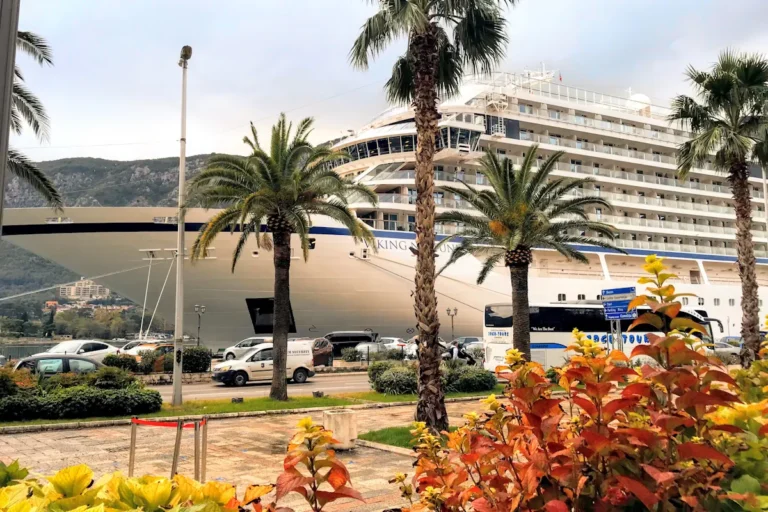 A large cruise ship docked at the Port of Kotor, located directly in front of the Old Town walls in Montenegro.