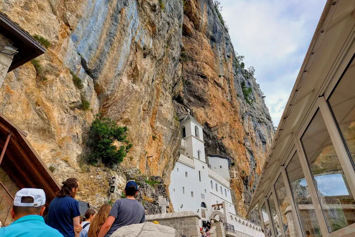 The white upper Ostrog Monastery in Montenegro and a line of pilgrims